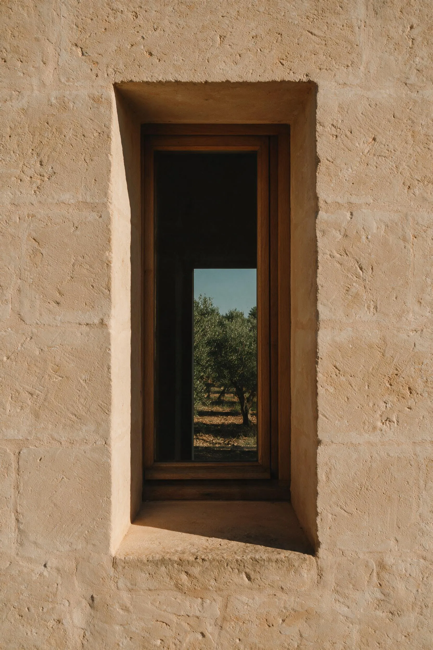 Ventana de madera colocada en un muro de piedra, con el encuentro constructivo resuelto en obra