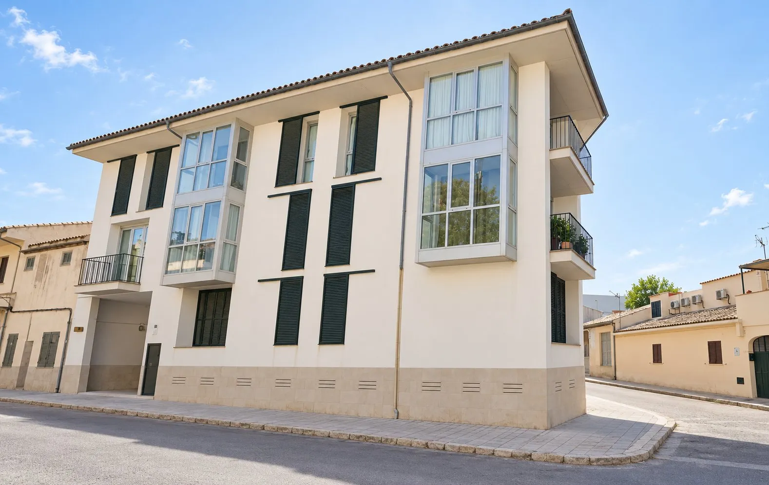 Fachada del edificio de 18 apartamentos del carrer Formentor de Pollença, con persianas verdes y miradores