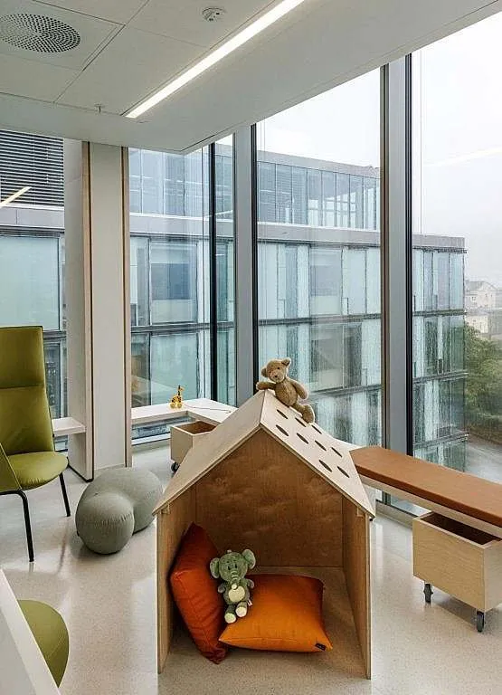 Sala de juegos de Glassblokkene con una casita de madera y cojines de colores