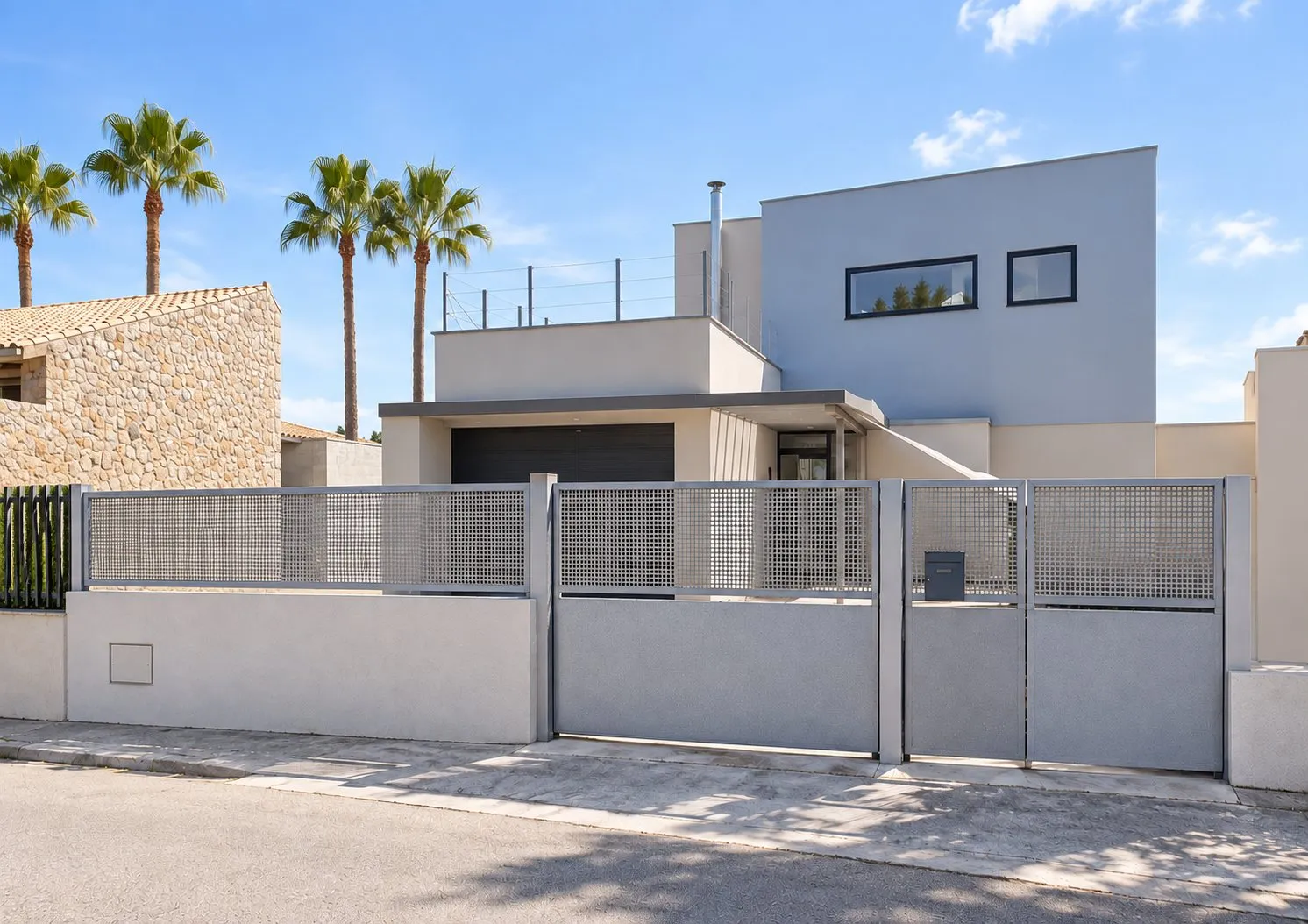 Fachada a calle de la vivienda Salbufereta, con el cierre de parcela y las palmeras