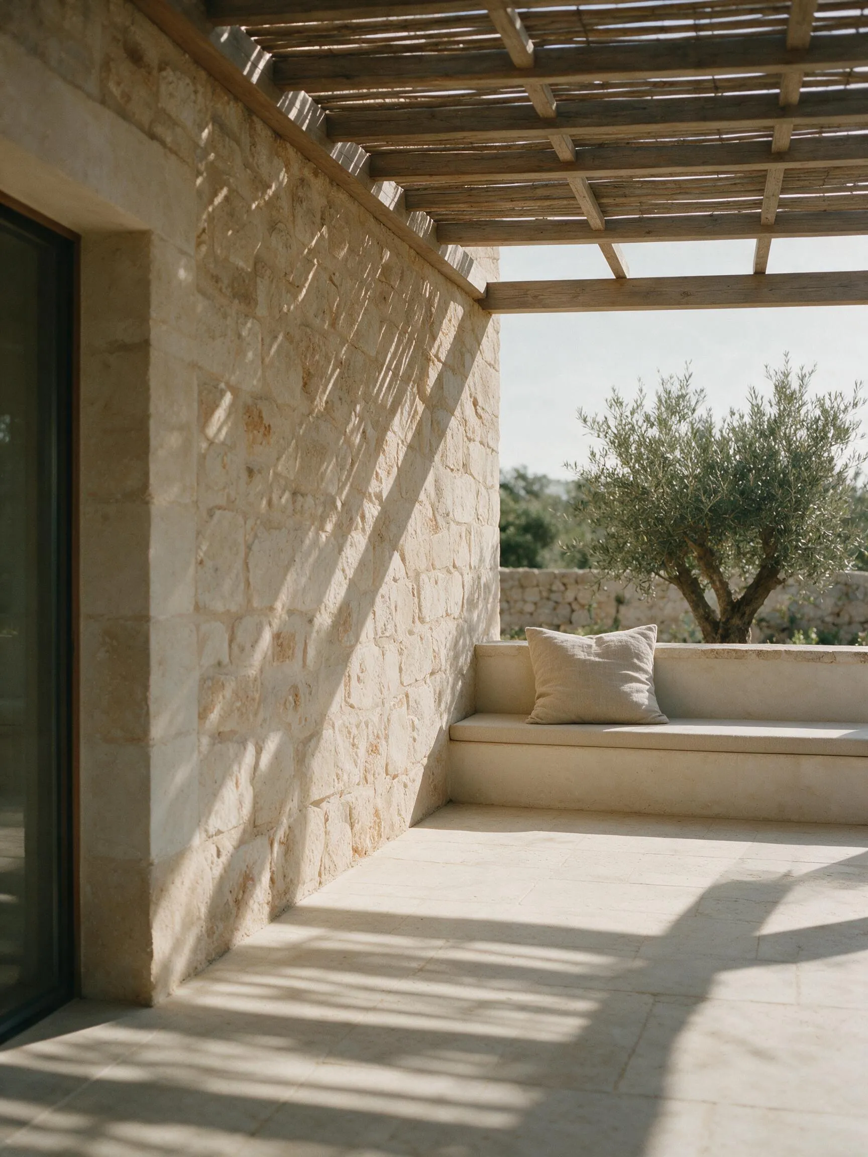 Terraza de una vivienda terminada en Mallorca con pérgola de madera y muro de piedra